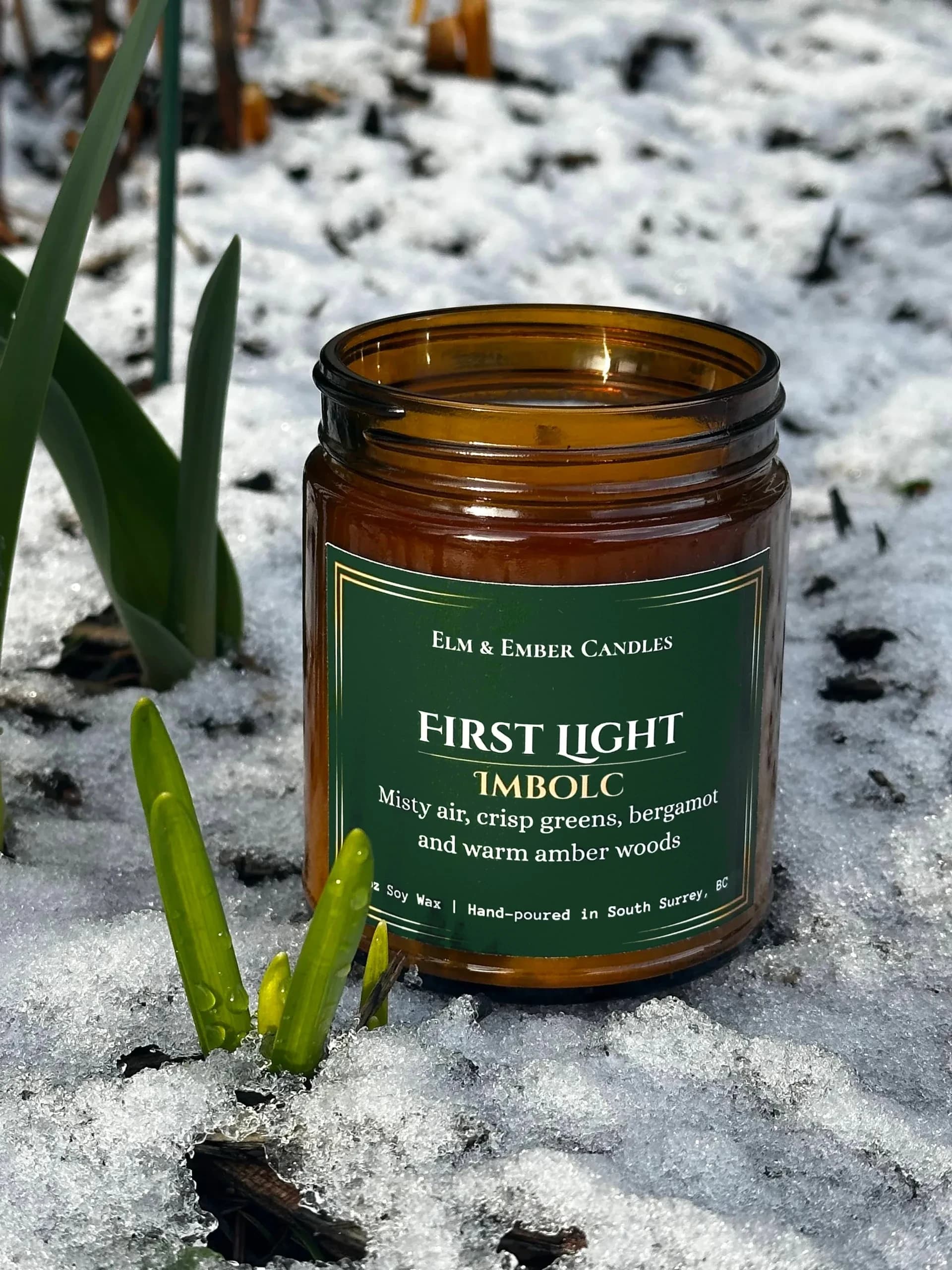 First Light candle in snow with snowdrops